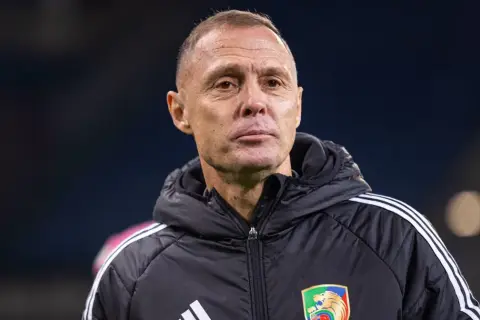 Trener Stali Mielec w czarnej kurtce z białymi pasami na ramionach, z emblematem klubu na piersi.