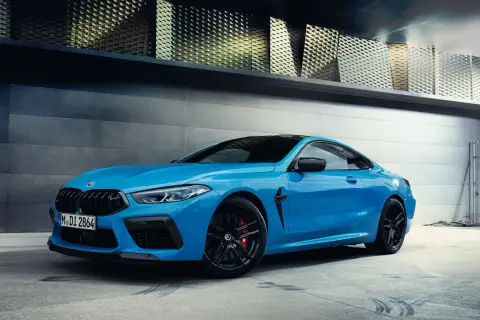 Niebieskie BMW M8 z czarnymi felgami i czerwonymi zaciskami hamulcowymi. Sprawdź aktualną bmw m8 cena.