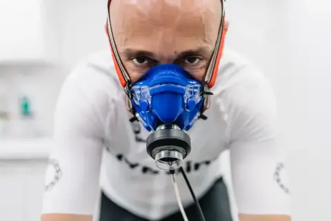 Intensywny trening, badanie **pułapu tlenowego**. Mężczyzna w masce analizującej oddech, skupiony na wysiłku.
