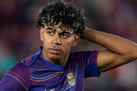 Lamine Yamal z FC Barcelony, zmartwiony po kontuzji, trzyma rękę za głową.
