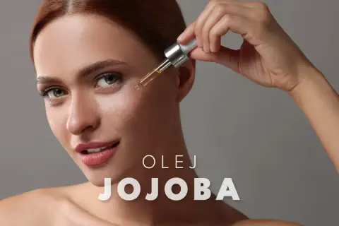Kobieta aplikuje kroplę olejku jojoba na twarz. Delikatna pielęgnacja dla promiennej cery.