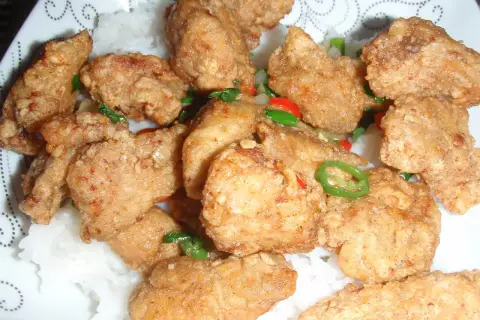 Chrupiący kurczak po koreańsku yangnyeom z podwójnie smażoną panierką ze skrobi, podany na ryżu z papryczkami chili.