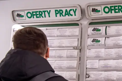 Mężczyzna przegląda ogłoszenia o pracę w urzędzie pracy. Szuka zatrudnienia, być może licząc na zasilek dla bezrobotnych.
