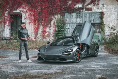 Mężczyzna prezentuje szarego McLarena 720S z otwartymi drzwiami. Zastanawiasz się nad mclaren 720s cena?