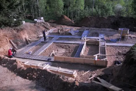 Prace budowlane w toku: trwa zalewanie fundamentów domu. Widać zbrojenie i szalunki.