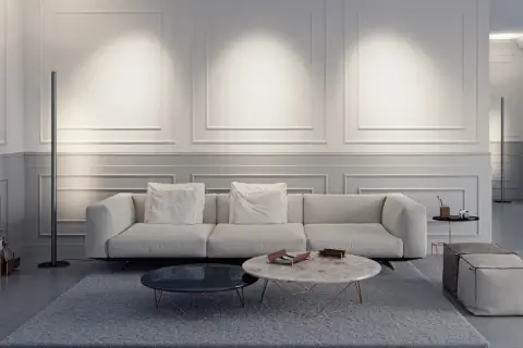 Elegante salón con sofá blanco, mesas de centro y una lámpara de pie sin pantalla que ilumina la pared con molduras.
