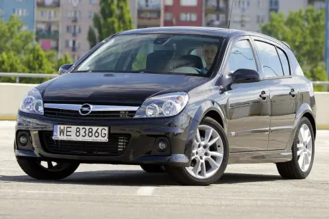 Czarny Opel Astra H na parkingu. Kierowca zastanawia się, jakie żarówki wybrać do swojego auta.