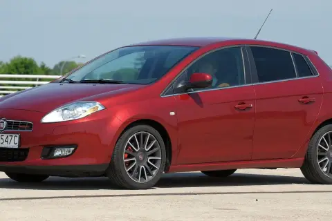 Czerwony Fiat Bravo 1.4 T-Jet z polskimi tablicami rejestracyjnymi SB 9547C zaparkowany na zewnątrz.