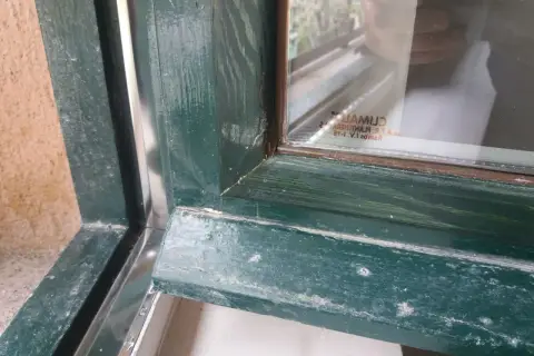 Detalle de marcos de madera antiguos pintados de verde, mostrando el proceso para aislar ventanas antiguas de madera y mejorar su eficiencia.