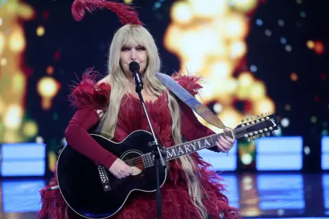 Maryla Rodowicz w pióropuszach i z gitarą, gotowa by zaśpiewać wszystkie przeboje.