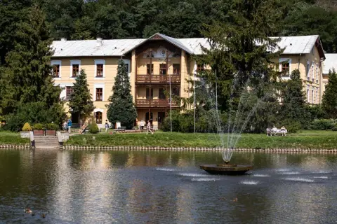 Piękny budynek sanatorium godne polecenia, z fontanną i stawem, otoczony zielenią.