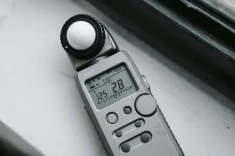 Srebrna jednostka oświetlenia EKO z kulistym dyfuzorem i wyświetlaczem pokazującym ISO 400, czas 125 i przysłonę 2.8.