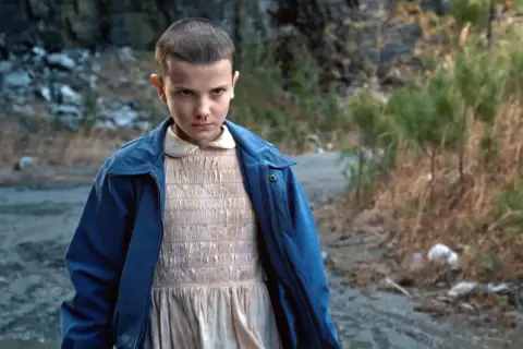 Nastka z Stranger Things, z nosem krwawiącym, stoi na brudnej drodze.