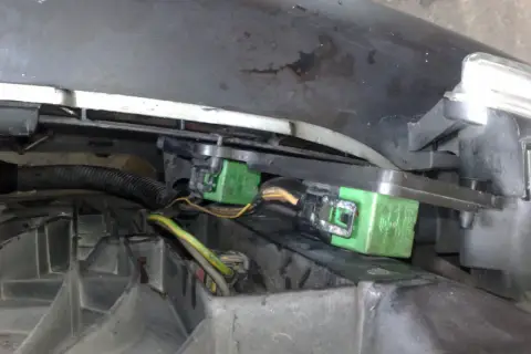 Zielone przekaźniki wentylatora chłodnicy w Peugeot 206, zamontowane pod maską, blisko reflektora.