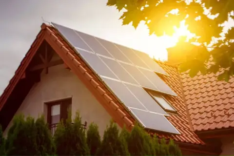 Panele fotowoltaiczne na dachu domu, symbolizujące przyszłość fotowoltaiki i zieloną energię. Słońce świeci jasno.