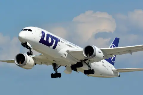 Boeing 787-8 Dreamliner LOT, z widocznym logo i napisem "POLISH AIRLINES". Samolot wznosi się na tle błękitnego nieba z chmurami.