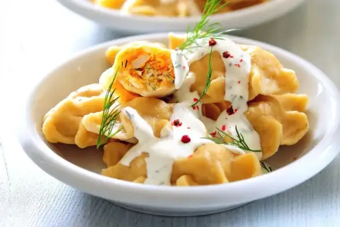 Pyszne pierogi z farszem, polane śmietaną i posypane koperkiem i pieprzem. Idealny obiad na sobotę.