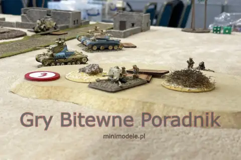 Miniaturowe czołgi i żołnierze na pustynnym polu bitwy. Sceneria do figurkowych gier bitewnych.