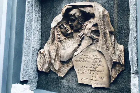 Rzeźba na kamiennej płycie przedstawia przytulonych kochanków. Cytat z Agnieszki Osieckiej mówi o miłości z ulicy Kamiennej.