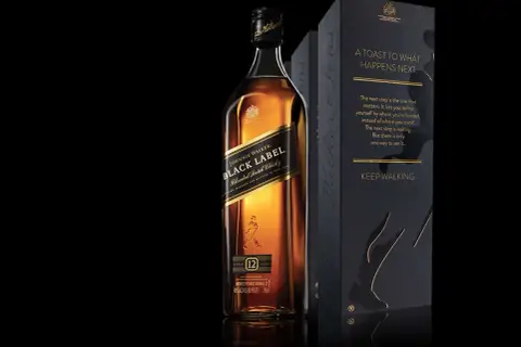 Elegancka butelka Johnnie Walker Black Label obok czarnego pudełka z cytatem "Keep Walking".
