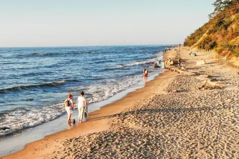 Spacer po plaży, idealne miejsce, gdzie jechać nad morze w listopadzie. Spokojne fale, piaszczysty brzeg i łagodne słońce.