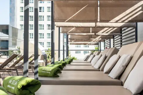 Tumbonas listas para el relax en la terraza del Meliá Valencia, con toallas verdes y vistas a la ciudad.