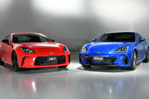 Dwa sportowe coupe, czerwona Toyota GR86 i niebieski Subaru BRZ, stoją obok siebie, gotowe do wyścigu.