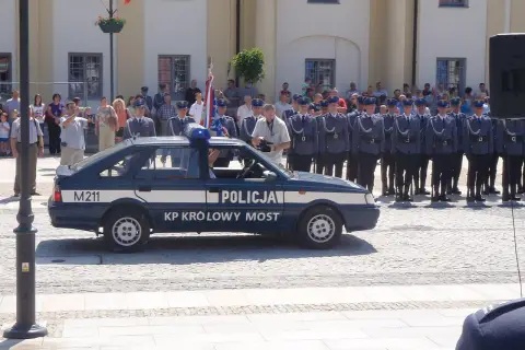 U pana Boga w ogródku obsada: policjanci w mundurach stoją w szeregu obok radiowozu.