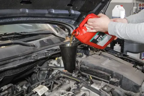 Wlewanie oleju ATF do skrzyni biegów. Czerwony kanister z płynem.