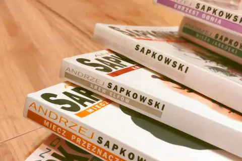 Stos książek Andrzeja Sapkowskiego, idealny przewodnik, jak czytać Wiedźmina od początku: Miecz Przeznaczenia, Krew Elfów, Czas Pogardy.