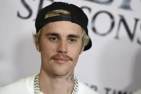Justin Bieber w czapce z daszkiem i z wąsami, wygląda jakby świętował swoje urodziny.
