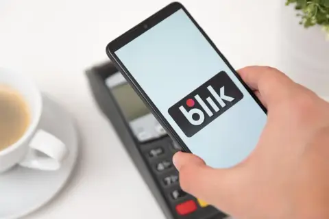 Zbliżeniowa płatność telefonem z logo Blik. Kawa czeka, a transakcja przebiega błyskawicznie.