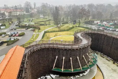 Wieliczka miasto. Drewniane tężnie solankowe tworzą malowniczą spiralę, a w tle widać zabudowania i park.