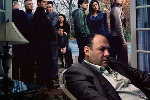 Rodzina Soprano zakończenie. Tony Soprano siedzi, otoczony przez członków rodziny i współpracowników, w napiętej atmosferze.