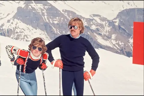 Robert Redford i jego dzieci na stoku narciarskim, w tle ośnieżone góry.