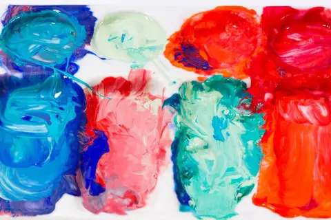 Farben auf einer Palette, bereit zum türkis mischen. Blau, Rot und Grün vermischen sich zu lebendigen Farbtönen.