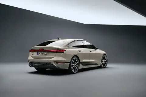 Elegancki tył nowego Audi A6 2025 w kolorze piaskowym, z charakterystycznym pasem świateł LED i sportowymi felgami.