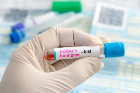 Rękawiczka medyczna trzyma probówkę z krwią do badania poziomu hormonów, w tym FSH.