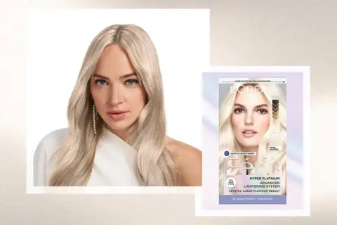 Mujer con pelo rubio platino, resultado de decoloración pelo. Caja de tinte L'Oréal Féria Hyper Platinum.