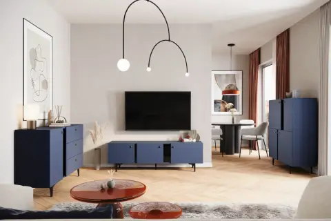 Nowoczesny salon z granatowymi meblami i ekstrawagancką lampą. W tle stół z krzesłami.