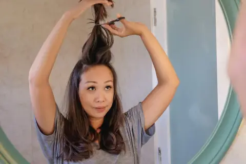 Mujer se corta el pelo en casa, creando un corte de pelo a capas.