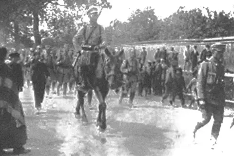 Żołnierze w historycznych mundurach, w tym na koniu, maszerują w zwartym szyku. To widok nawiązujący do czasów, gdy formowały się legiony polskie.