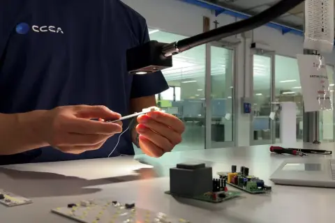 Técnico ensambla componentes electrónicos bajo una luz focalizada, asegurando cada lumen unidad.
