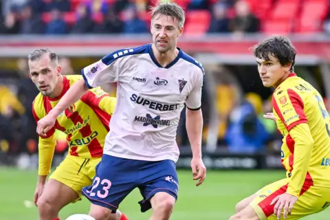 Piłkarze Górnika Zabrze i Korony Kielce walczą o piłkę. Mecz w deszczu, kibice na trybunach.