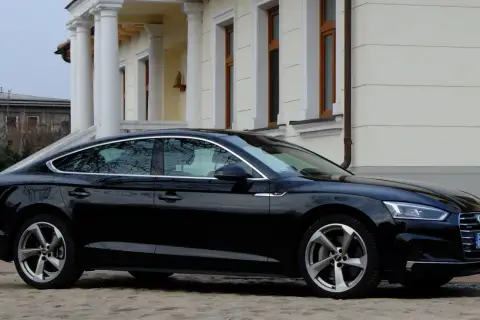 Eleganckie, czarne Audi A5 z 2018 roku zaparkowane przed klasycznym budynkiem z kolumnami.