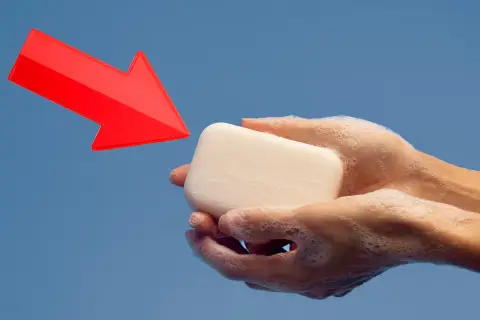 Manos enjabonadas sostienen jabón neutro. Una flecha roja apunta hacia él, indicando su uso.