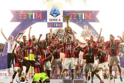 Piłkarze świętują zdobycie scudetto, unosząc puchar Serie A wśród konfetti i fajerwerków.