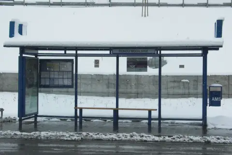 Przystanek Rondo Mogilskie zasypany śniegiem. Wiaty, ławka i kosz na śmieci pokryte białym puchem.