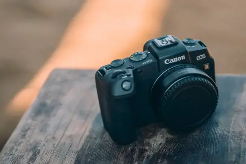 Czarny aparat Canon EOS RP leży na drewnianym blacie. Idealny do canon rp testów.