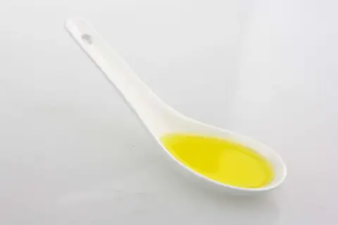 Ein Löffel mit goldenem Olivenöl. Achten Sie auf die Olivenöl Kalorien, wenn Sie es genießen.